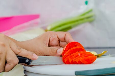 women hand cuting tomato on boardの写真素材