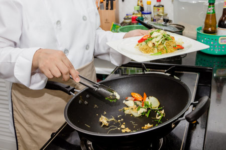 chef making chinese stir-fried noodles in pan
