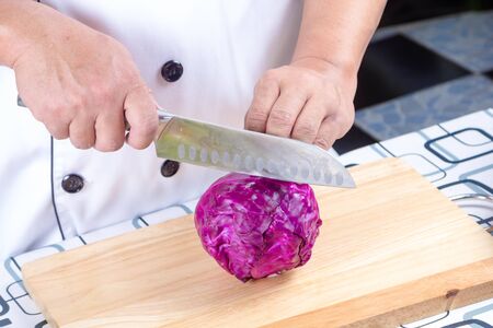 chef cutting purple cabbage on wooden boardの写真素材