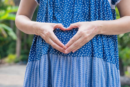 Woman holding hands in a heart shape on pregnantの写真素材