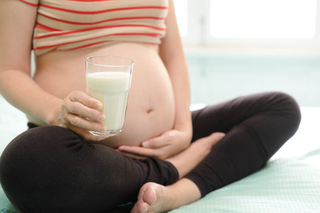 pregnant woman holding cup of milkの写真素材