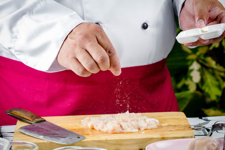 chef seasoning raw chicken on wooden boardの写真素材