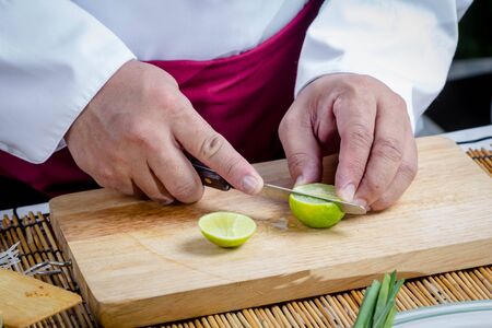 Chef slicing Lime on wooden cutting boardの写真素材