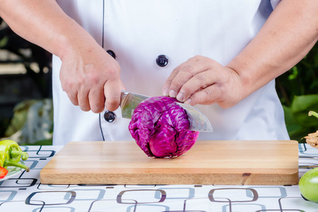 chef cutting purple cabbage on wooden boardの写真素材