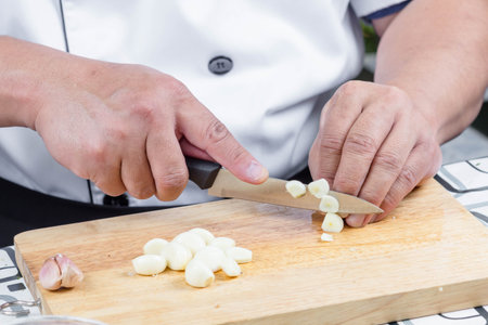 chef sliced garlic on wooden b