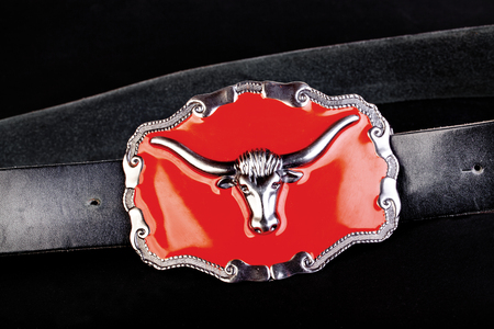 Black leather belt with red buckle on a black backgroundの写真素材