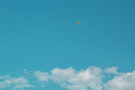 Flying kite in the blue sky against the background of cloudsの写真素材