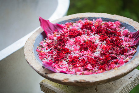 Stone bowl of aroma of petals of pink and red flowers in a spa bath