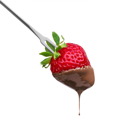 Fondue strawberry soaked in hot black chocolate on a fork isolated on white backgroundの写真素材