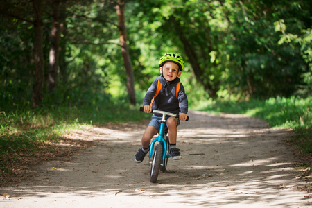 Toddler four years riding a balance bike along the path in the park on a sunny summer dayの写真素材