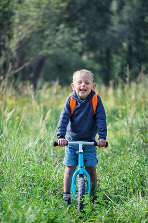 Little boy riding a balance bike along the path in the park on a sunny summer dayの写真素材