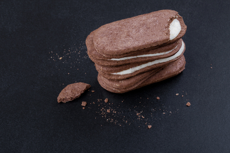 Chocolate sandwich cookies with white cream filling on a black background, close-up top viewの写真素材