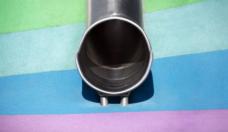 Empty round metal slide tube on the playground, without children