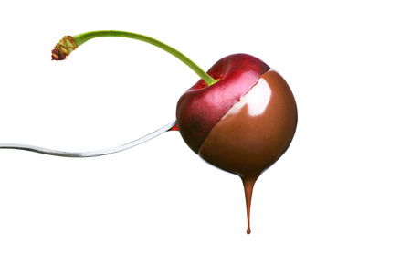 Fondue cherry in hot chocolate on a fork isolated on a white backgroundの写真素材