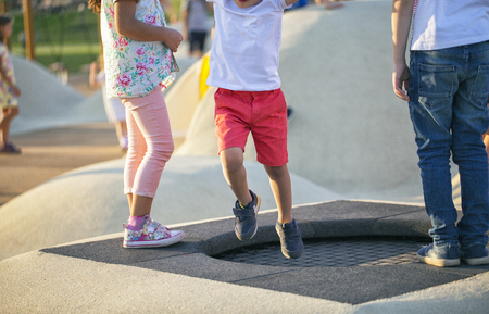 Boy jumping on trampoline on the playground in the parkの写真素材