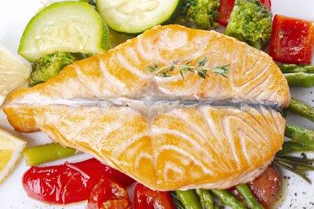 Grilled salmon steak butterfly with vegetables and asparagus on a white plateの写真素材