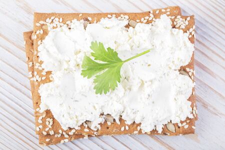 Sesame cracker with ricotta on a wooden white tableの写真素材