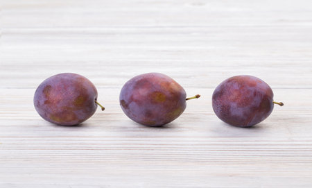 Ripe plums on a wooden white tableの写真素材