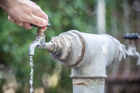 A man tries to open a tap of water / hand opens a water tap.の写真素材