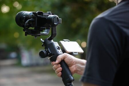 Man holding a camera with gimbal stabilizer outdoor.の写真素材