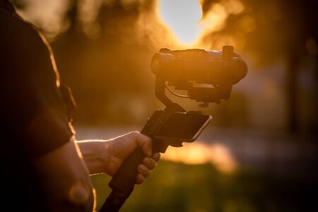 Man holding a camera with gimbal stabilizer outdoor.の写真素材