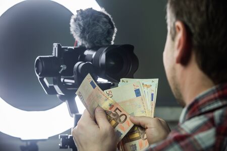 Male vlogger counting money from vloggingの写真素材