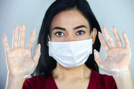 A woman putting on a medical disposable mask to avoid contagious viruses.の写真素材