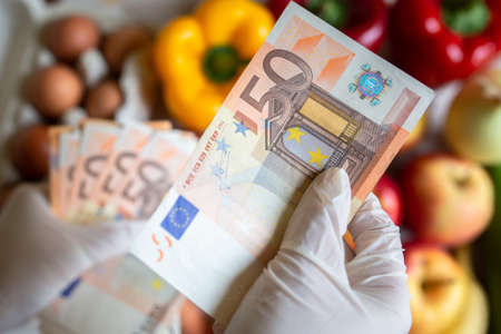 Buyer handing money wearing rubber gloves to prevent the spread of bacterias or viruses. / overbuying food due to the coronavirus epidemic/ shopping during coronavirus outbreak.の写真素材