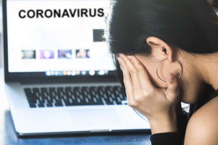 Coronavirus concept:  A woman reading news/updates about coronavirus and getting anxiety/depression.の写真素材