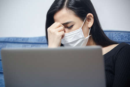 Coronavirus outbreak:  A woman reading news/updates about coronavirus and getting anxiety/depression. Global pandemic. Isolation against Coronavirus. Lockdown mental health.の写真素材