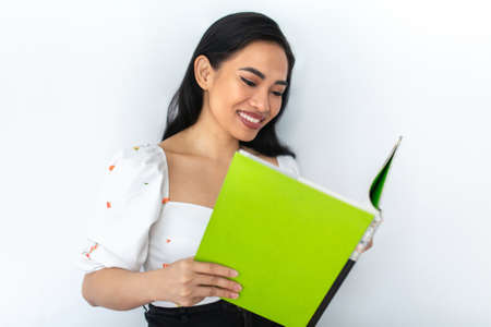 Beautiful Asian woman smiling reading a book / Studying at home.の写真素材