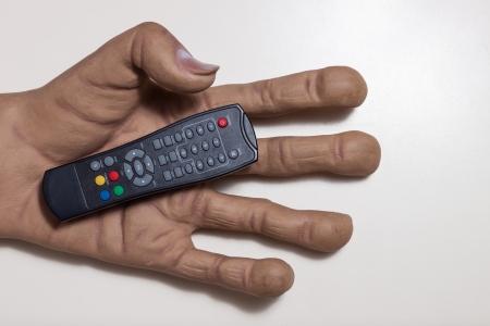 Top view of huge hand holding a tv remote controlの写真素材