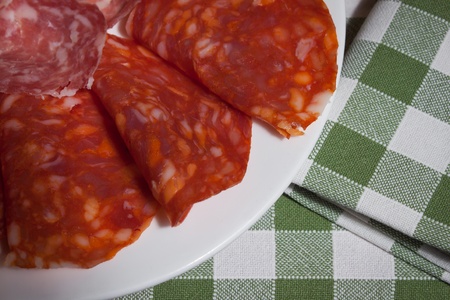 Detail of a plate of italian spicy salami on green and withe tableclothの写真素材