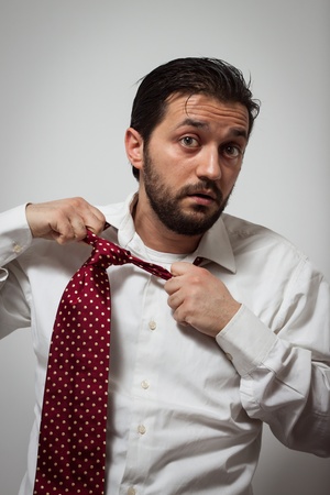 Young bearded man removing his red tieの写真素材