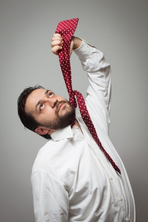Young bearded man pretending to hang himself with a red  tieの写真素材