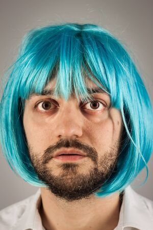 Funny bearded man with a blue wig on grey backgroundの写真素材