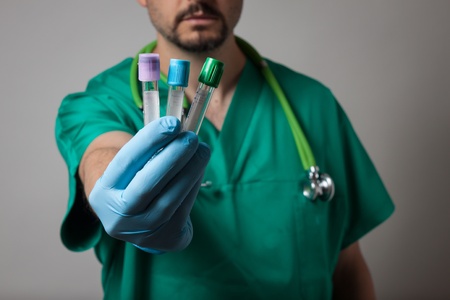 Physician with green uniform holding test tubesの写真素材