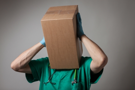 Doctor with cardboard box head in green uniformの写真素材