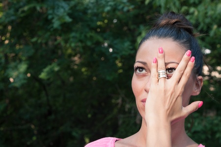 Portrait of a beautiful girl covering her face with one handの写真素材