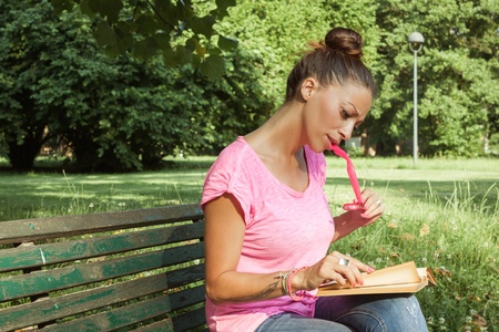 Portrait of a beautiful girl reading book on benchの写真素材