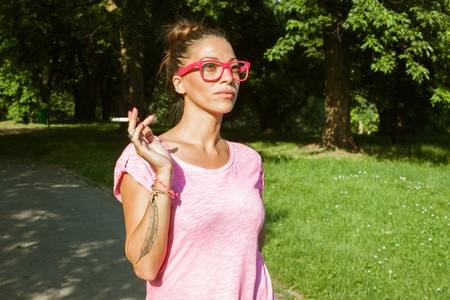 Portrait of a beautiful girl smoking cigarette in city parkの写真素材