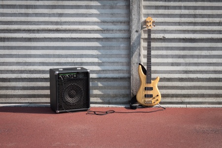 Bass guitar and amplifier against a concrete wallの写真素材