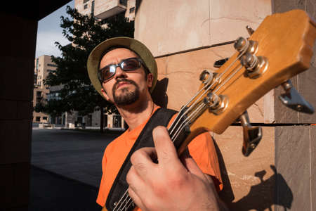 Young musician playing bass guitar in the streetの写真素材