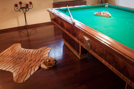Billiard table with mock tiger skin rug on parquet floor
