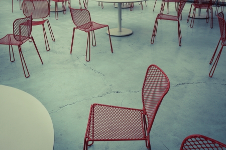 Red metal chairs scattered on concrete floorの写真素材