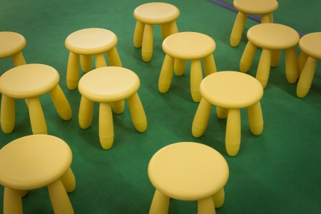 Yellow stools scattered on green floorの写真素材