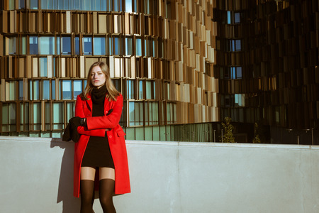 Beautiful girl posing in the street with red coat の写真素材