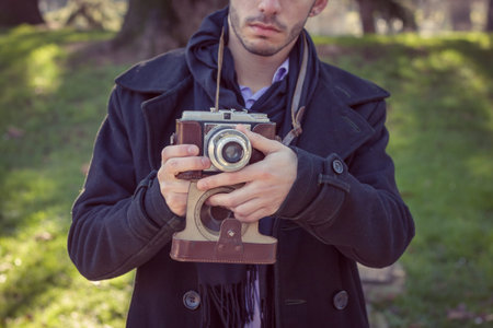 Portrait of a handsome young man with vintage cameraの写真素材