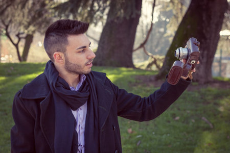 Portrait of a handsome young man taking a selfie with vintage camera