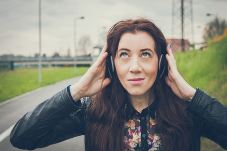 Pretty girl with long hair and black leather jacket listening to musicの写真素材